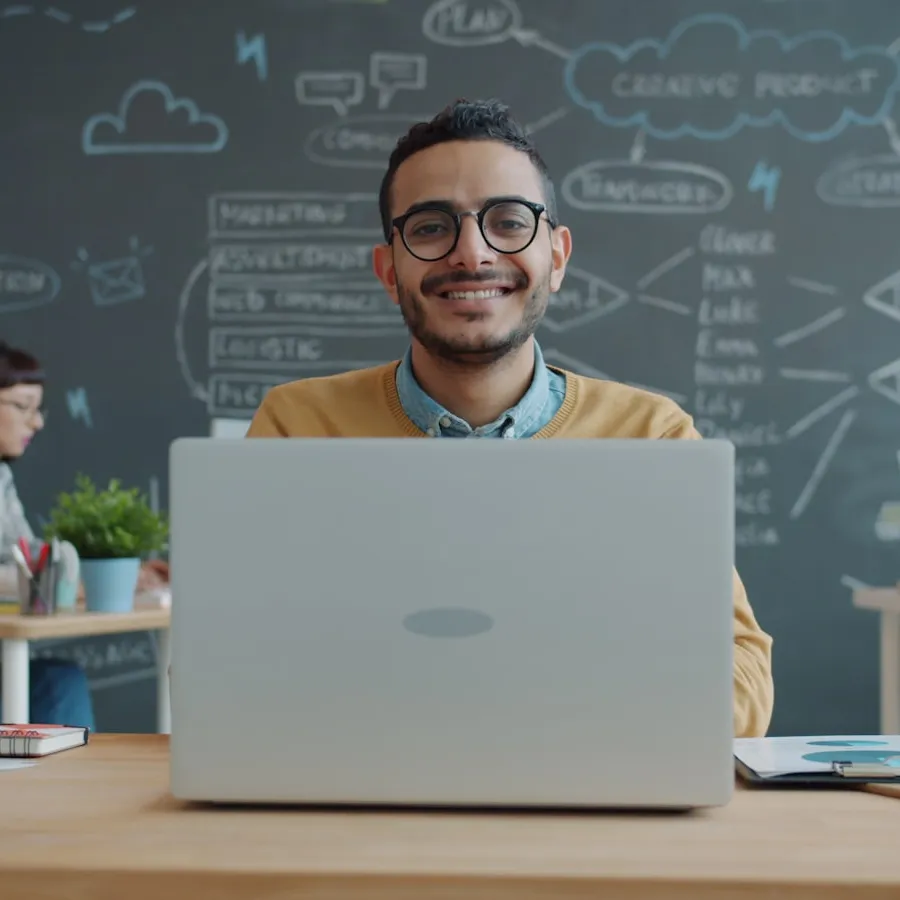 Hombre sonriente trabajando con su portátil en la oficina