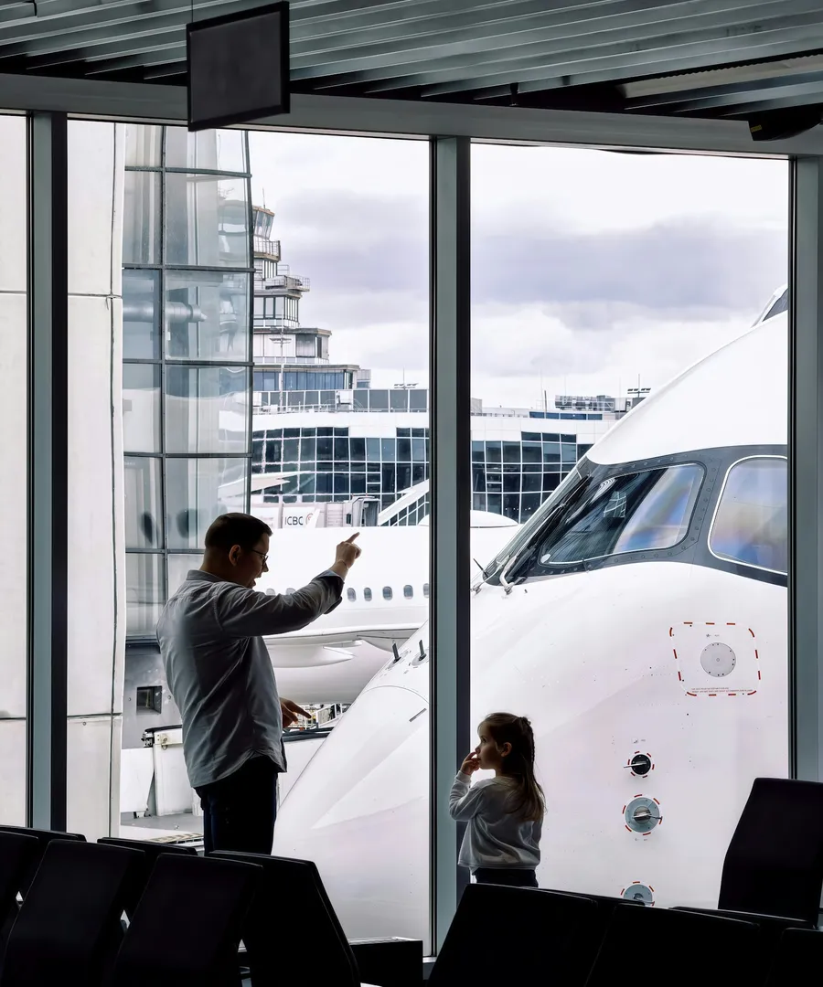 Padre e hija esperando la llegada de un familiar en el aeropuerto